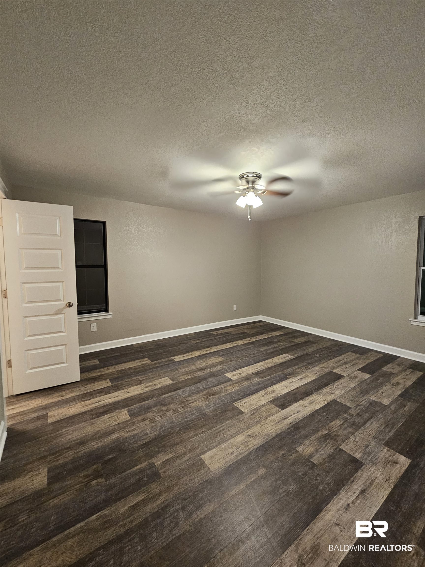 138 Wicker Way Daphne, AL 36526 - Photo 11 of 32 Empty room featuring dark wood-style floors, a textured ceiling, and a ceiling fan