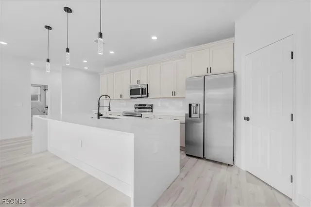 a large white kitchen with a refrigerator a sink and a stove