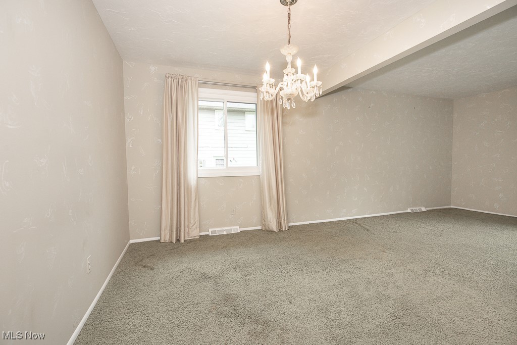 4569 McFarland Road Cleveland, OH 44121 - Photo 13 of 29 Spare room featuring baseboards, visible vents, an inviting chandelier, and carpet flooring