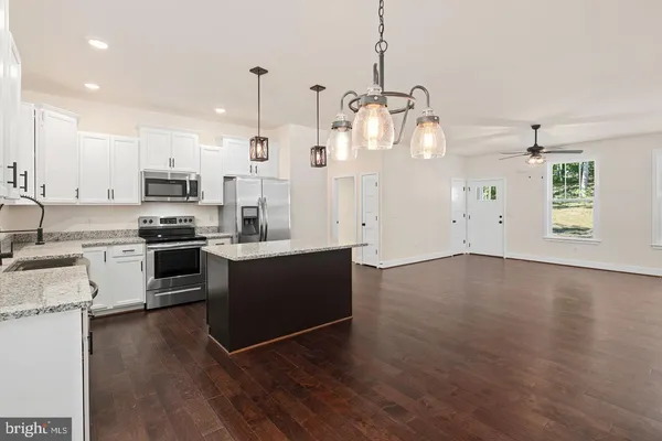 a kitchen with stainless steel appliances kitchen island granite countertop a stove a sink and a refrigerator