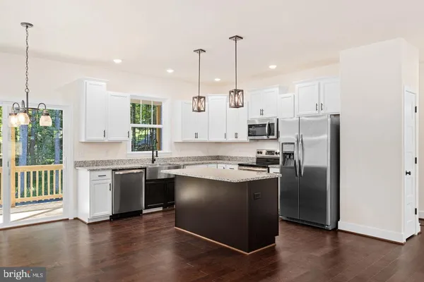 a kitchen with stainless steel appliances granite countertop a refrigerator a sink a stove and a wooden floor