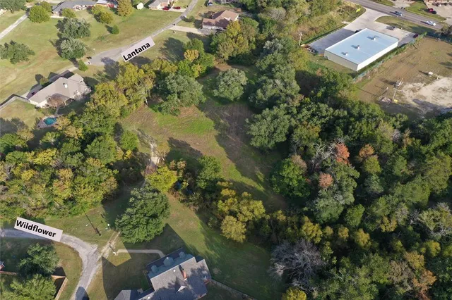 an aerial view of residential house with outdoor space and trees all around