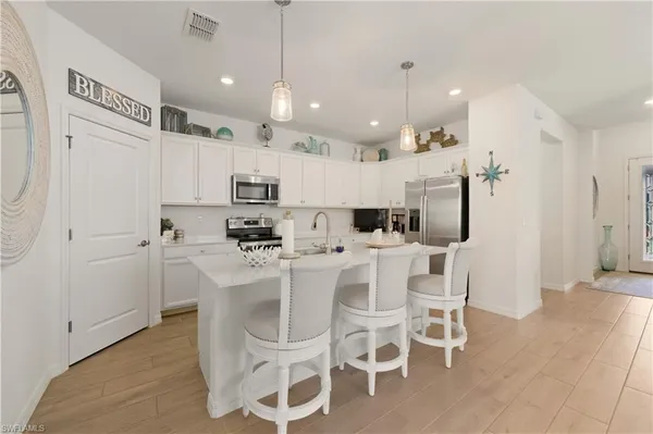 a kitchen with stainless steel appliances kitchen island granite countertop a dining table chairs and sink