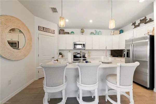 a kitchen with stainless steel appliances a white table chairs and a refrigerator