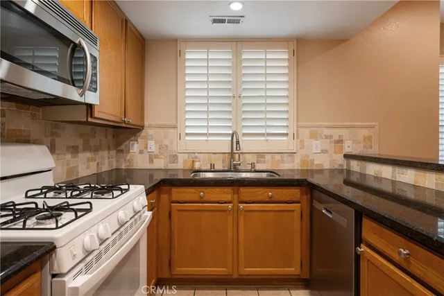a kitchen with granite countertop cabinets stainless steel appliances a sink and a window