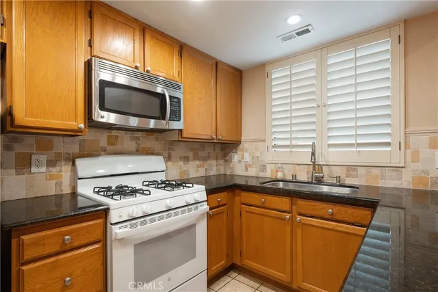 a kitchen with granite countertop stainless steel appliances a refrigerator cabinets and a sink