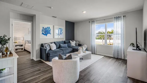 a living room with furniture large window and wooden floor