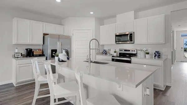 a kitchen with stainless steel appliances a stove a sink a refrigerator white cabinets and wooden floor
