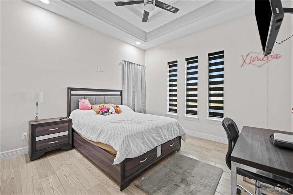 1110 Raptor Street Palmview, TX 78572 - Photo 17 of 31 Bedroom featuring light wood finished floors, an office area, a ceiling fan, a raised ceiling, and recessed lighting