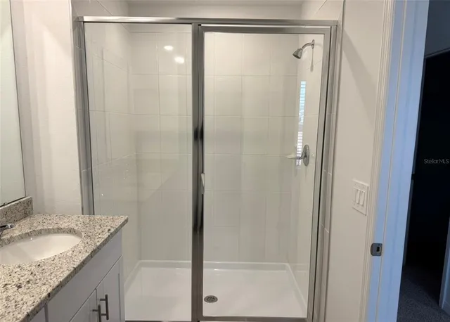 a bathroom with a granite countertop shower and a sink