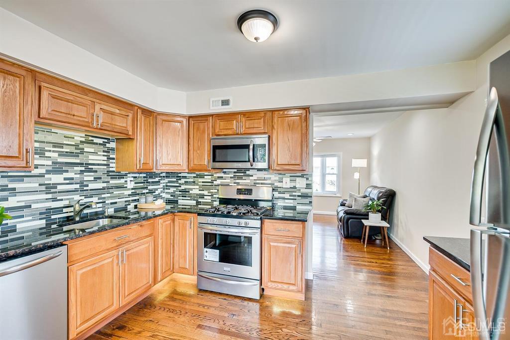 119 Wagner Street Edison, NJ 08837 - Photo 15 of 41 a kitchen with stainless steel appliances granite countertop wooden cabinets a sink a stove a dining table and chairs