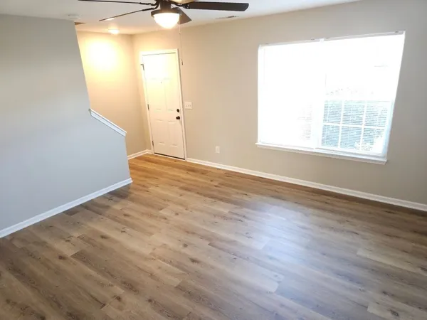 an empty room with wooden floor and windows