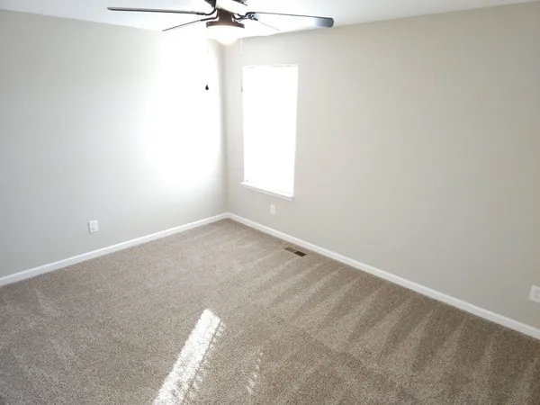 an empty room with a window and a fan