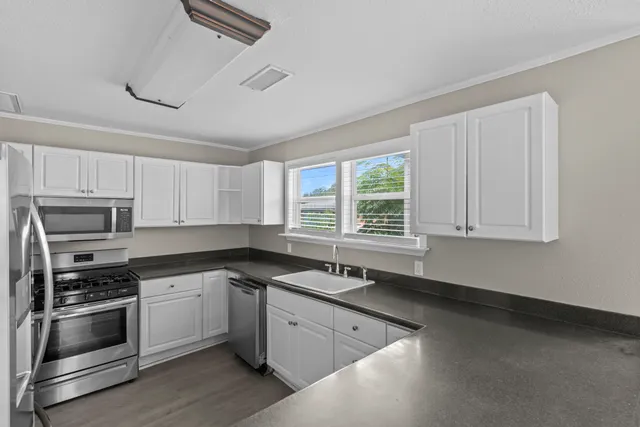 a kitchen with granite countertop white cabinets and stainless steel appliances