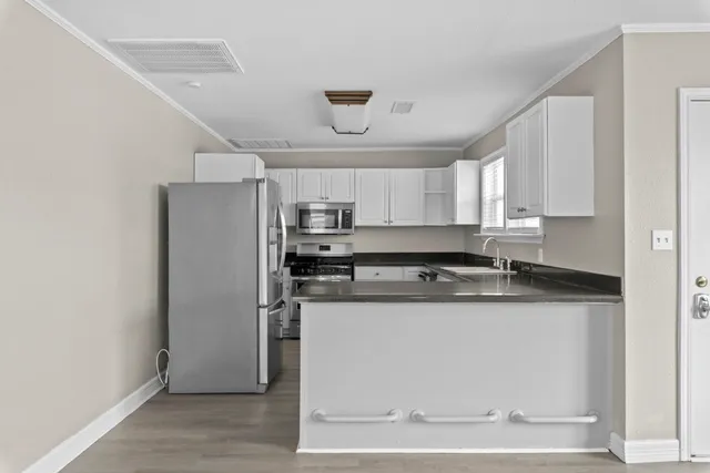 a kitchen with stainless steel appliances granite countertop a refrigerator a sink a stove and white cabinets