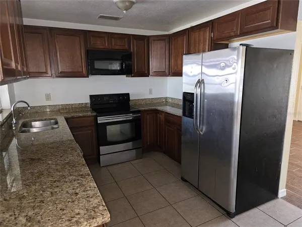 a kitchen with granite countertop a refrigerator and a stove top oven