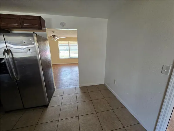 a view of a refrigerator in kitchen and an empty room