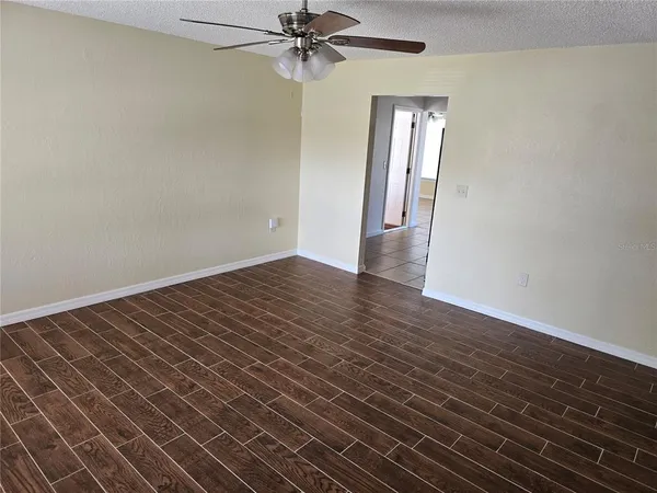 a view of an empty room with wooden floor and a window