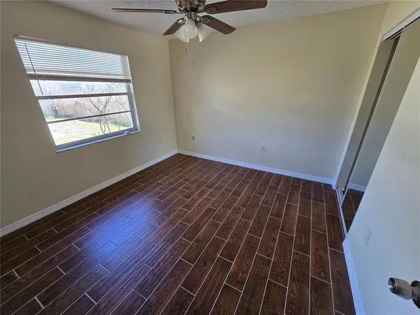 a view of an empty room with wooden floor and a window