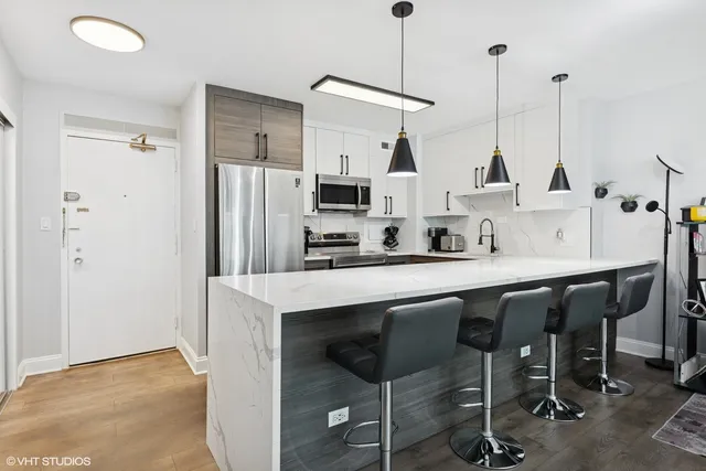 a kitchen with stainless steel appliances a sink a stove a refrigerator and island with wooden floor