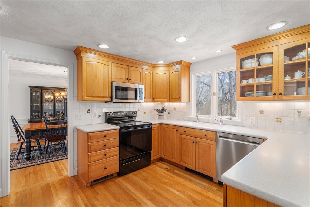 4 Greybirch Road Andover, MA 01810 - Photo 8 of 42 a kitchen with stainless steel appliances granite countertop a stove top oven a sink dishwasher a dining table and chairs with wooden floor