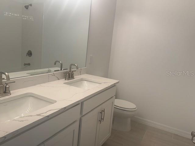 5472 Hanover Square Drive St. Cloud, FL 34771 - Photo 5 of 7 a bathroom with a granite countertop sink a toilet and a mirror