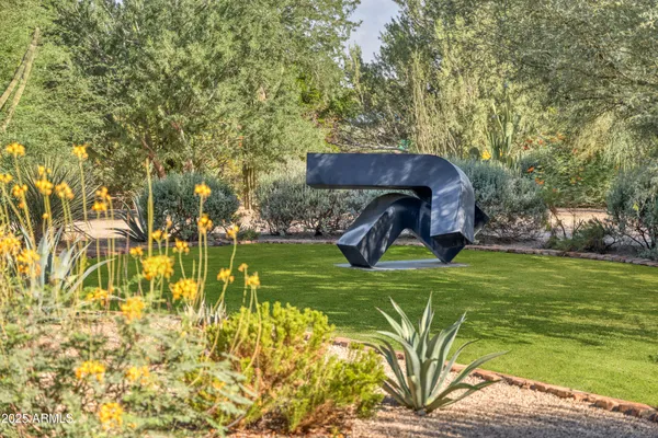 a view of a table and chairs under an umbrella with large trees