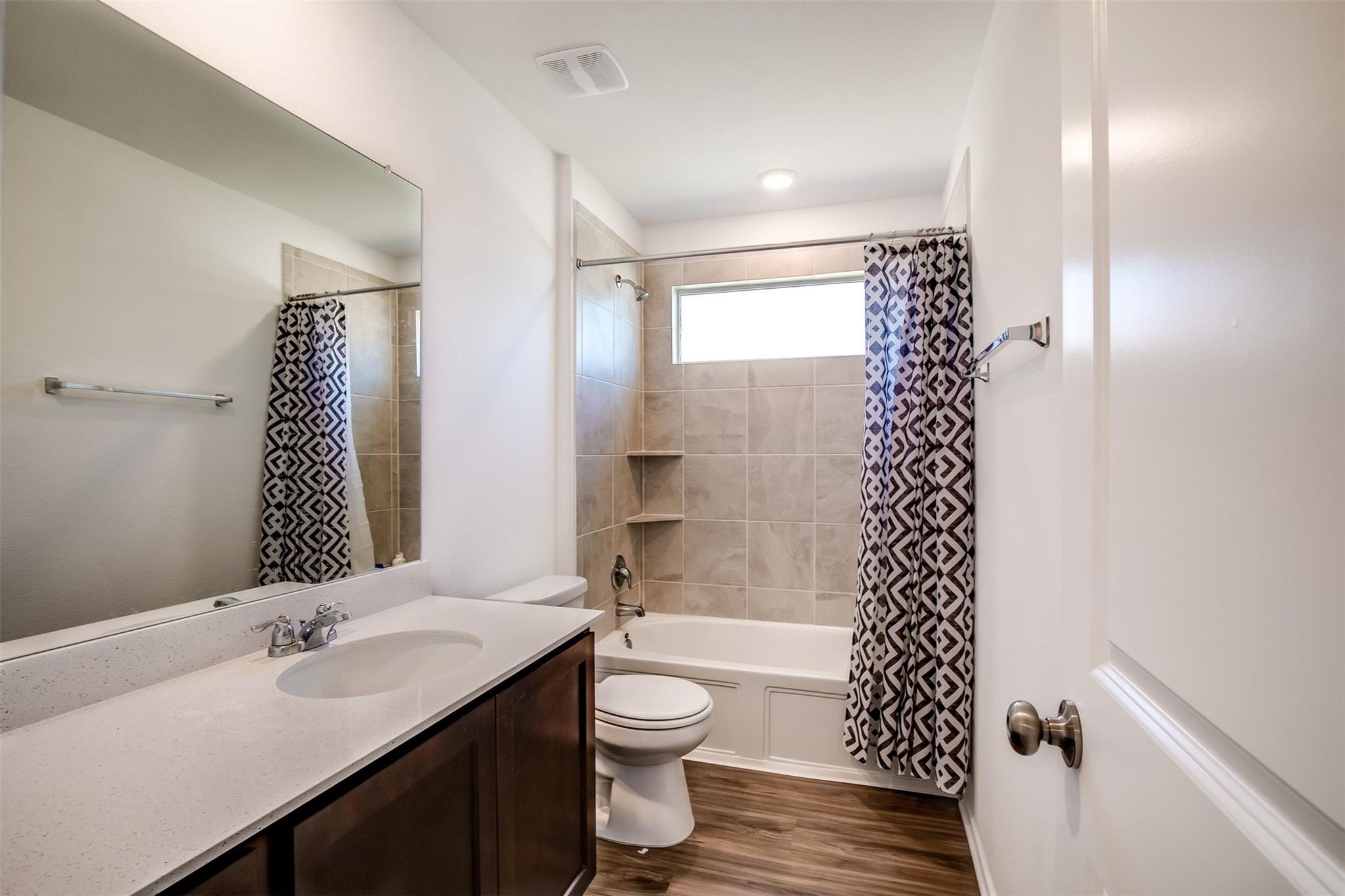 614 Milliner Loop Hutto, TX 78634 - Photo 9 of 25 A well-lit bathroom features a deep soaking tub and a sleek vanity with ample counter space.