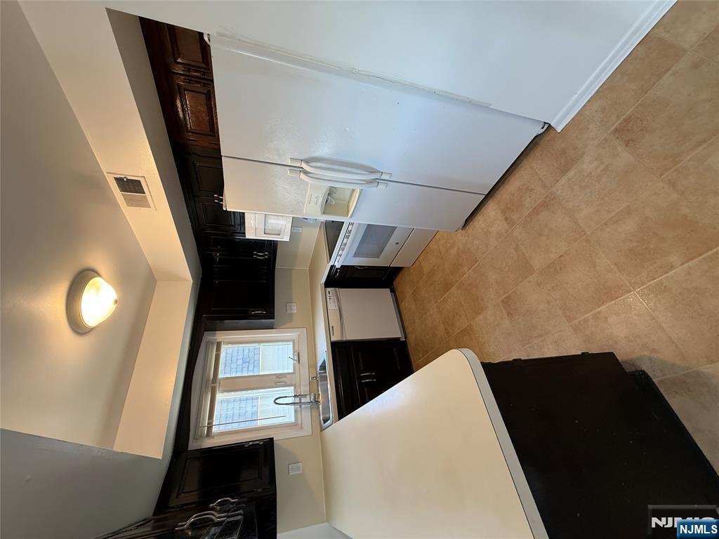 1276 River Road, Unit 2 Edgewater, NJ 07020 - Photo 7 of 16 a kitchen with stainless steel appliances kitchen island granite countertop a refrigerator a sink dishwasher and wooden cabinets