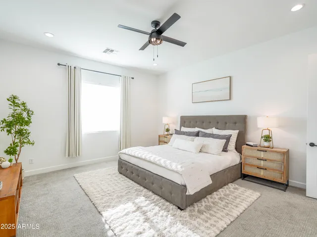 a bedroom with a large bed and a chandelier fan