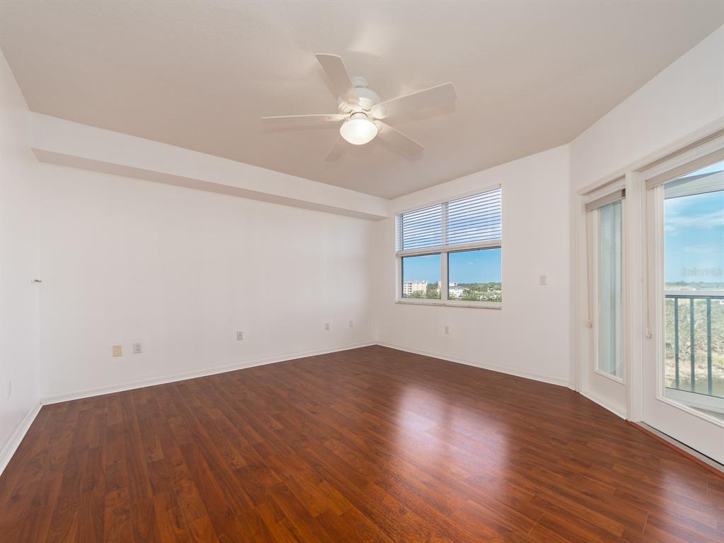 6550 Shoreline Drive, Unit 7502 St. Petersburg, FL 33708 - Photo 12 of 30 an empty room with wooden floor fan and windows