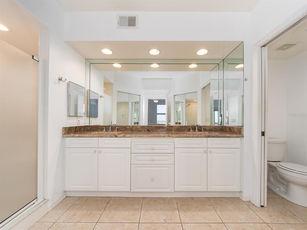 6550 Shoreline Drive, Unit 7502 St. Petersburg, FL 33708 - Photo 16 of 30 a bathroom with a granite countertop sink a toilet and a mirror