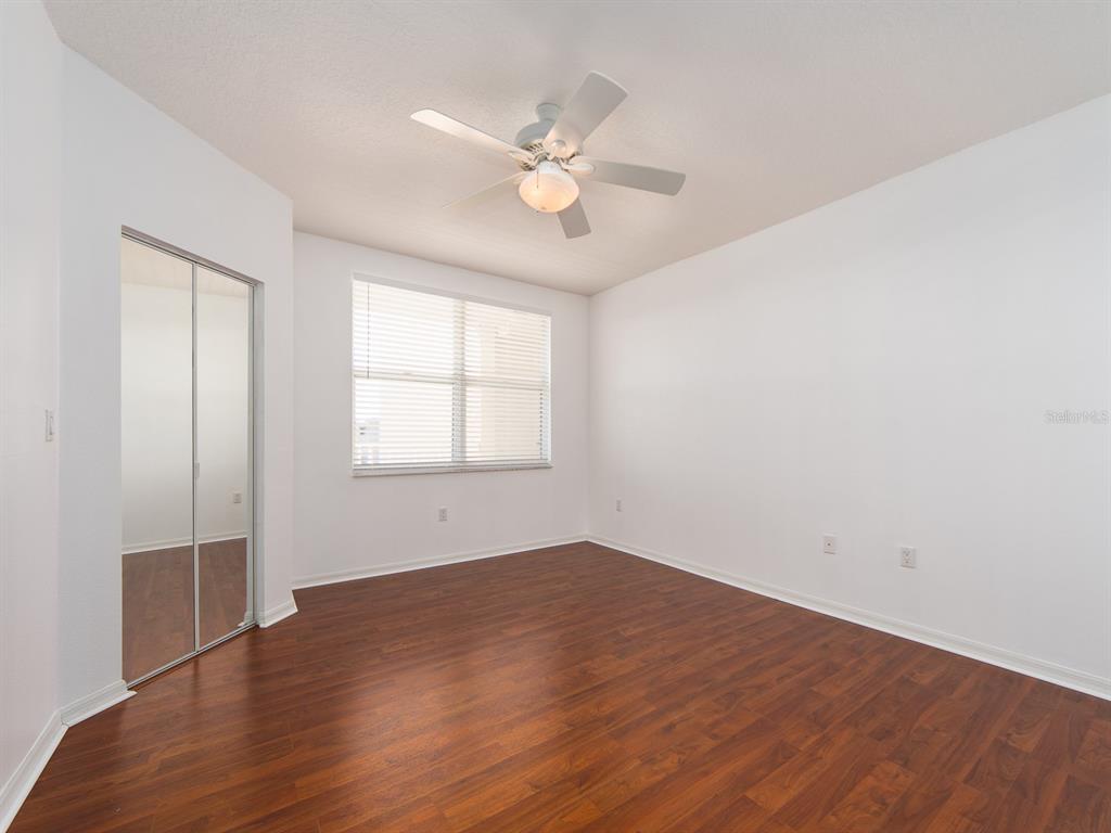6550 Shoreline Drive, Unit 7502 St. Petersburg, FL 33708 - Photo 18 of 30 an empty room with wooden floor fan and windows