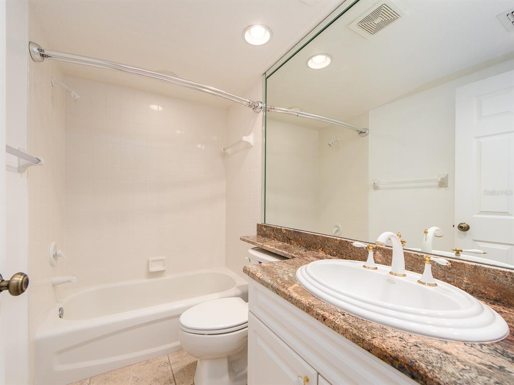 6550 Shoreline Drive, Unit 7502 St. Petersburg, FL 33708 - Photo 20 of 30 a bathroom with a granite countertop sink a toilet and shower