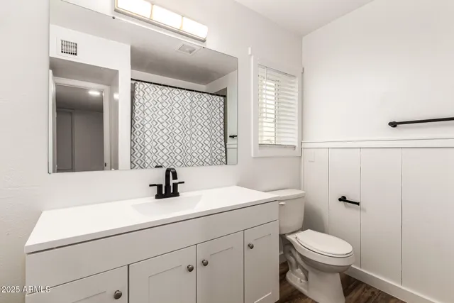 a bathroom with a sink a toilet a mirror and shower