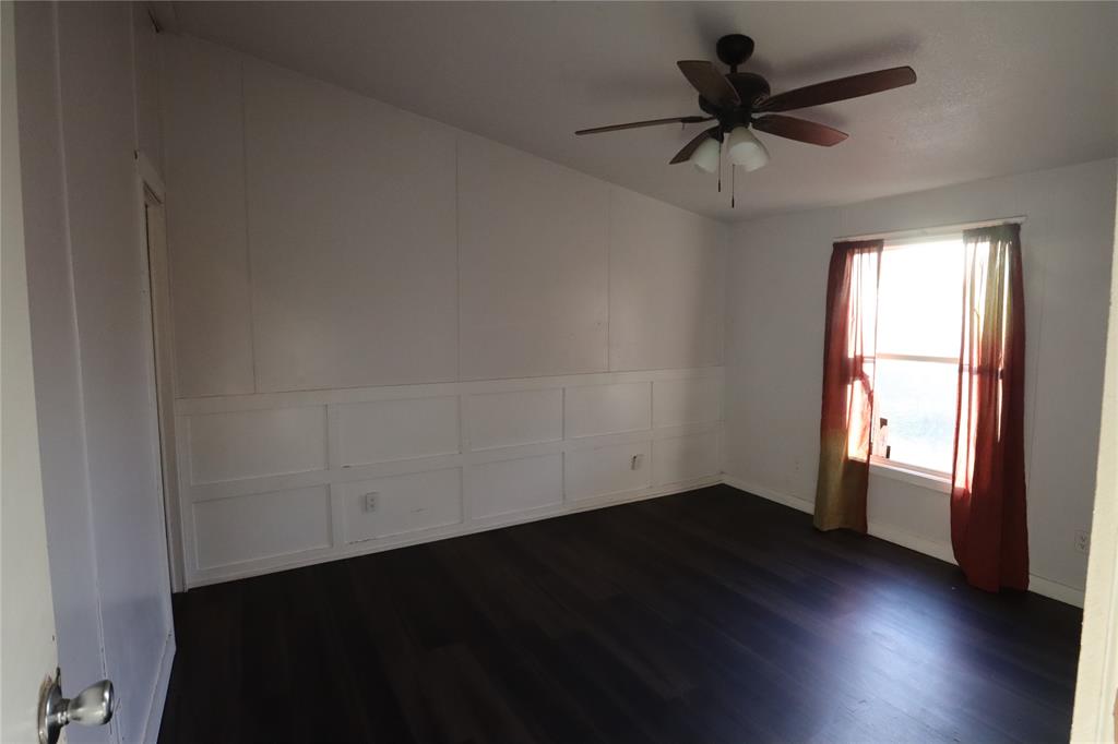 1437 West Loop 254 Ranger, TX 76470 - Photo 16 of 27 an empty room with wooden floor fan and windows