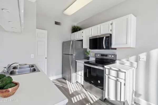 a kitchen with stainless steel appliances a stove a sink a refrigerator and a microwave