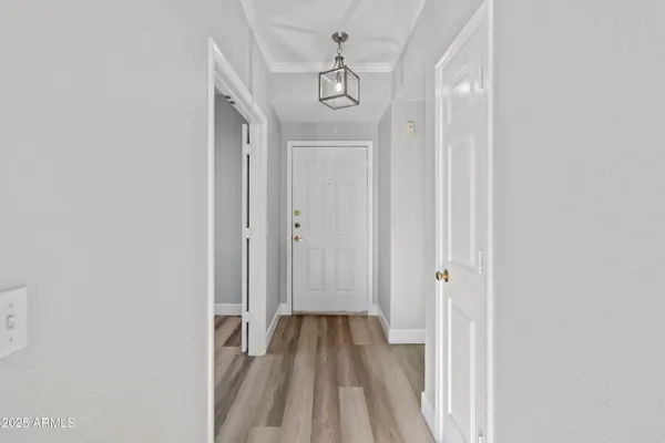 a view of a hallway with wooden floor and a chandelier
