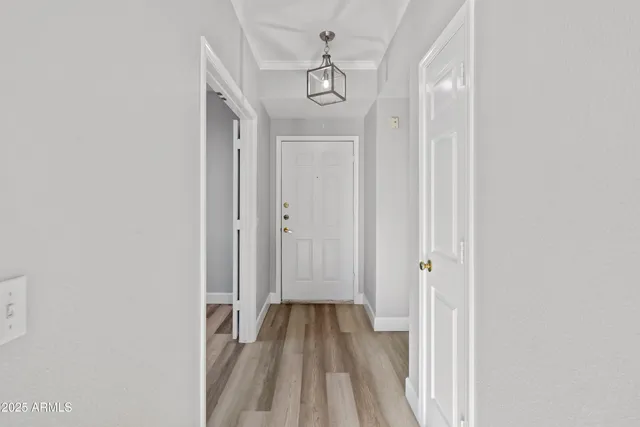 a view of a hallway with wooden floor and a chandelier