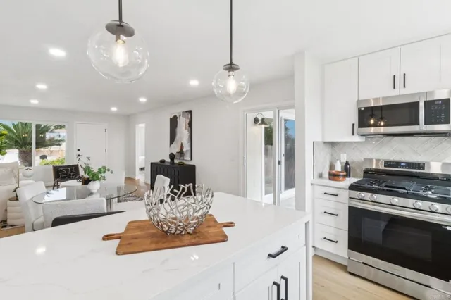 a kitchen with stainless steel appliances a stove center island a stove cabinets a dining table and chairs