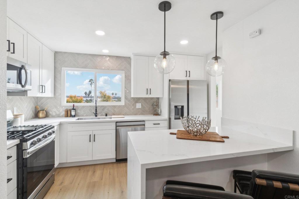 4723 Rim Rock Road Oceanside, CA 92056 - Photo 10 of 29 a kitchen with a sink a stove a refrigerator and white cabinets