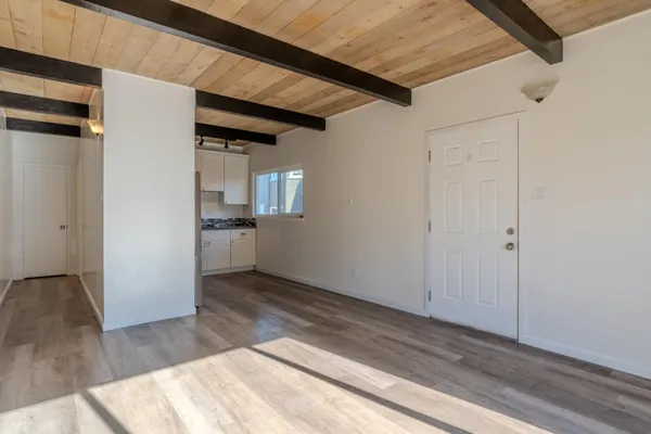 a view of a hallway with wooden floor and a kitchen
