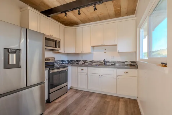 a kitchen with granite countertop a sink stainless steel appliances and white cabinets