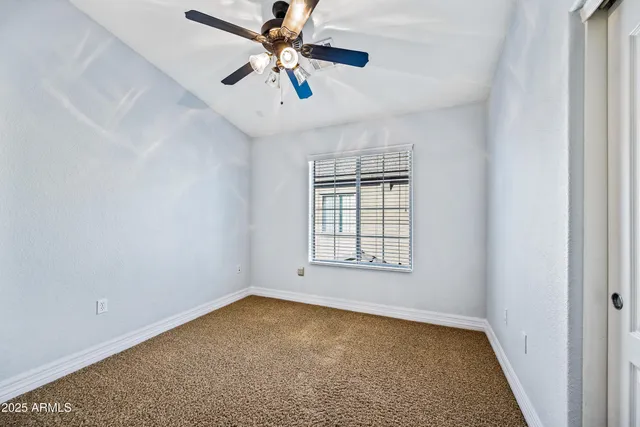 an empty room with chandelier fan and windows