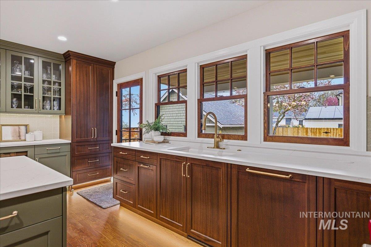 1210 North Harrison Boulevard Boise, ID 83702 - Photo 11 of 39 Kitchen with glass insert cabinets, light wood-style floors, recessed lighting, light stone counters, and tasteful backsplash