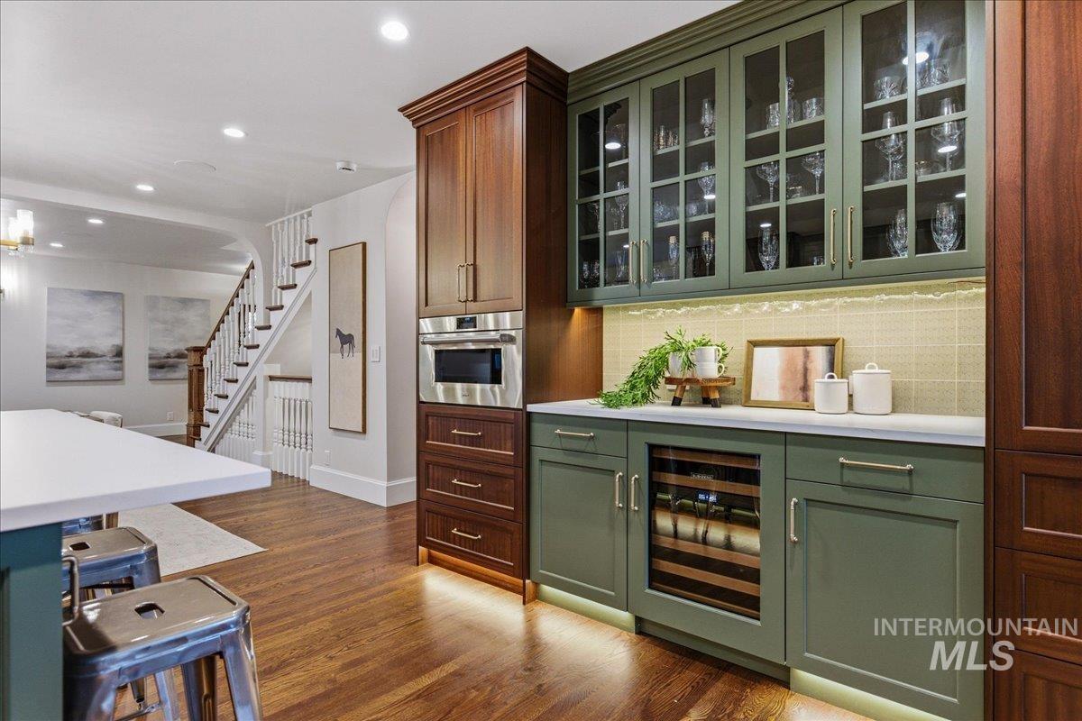 1210 North Harrison Boulevard Boise, ID 83702 - Photo 12 of 39 Bar featuring green cabinets, glass insert cabinets, beverage cooler, dark wood-style floors, and oven