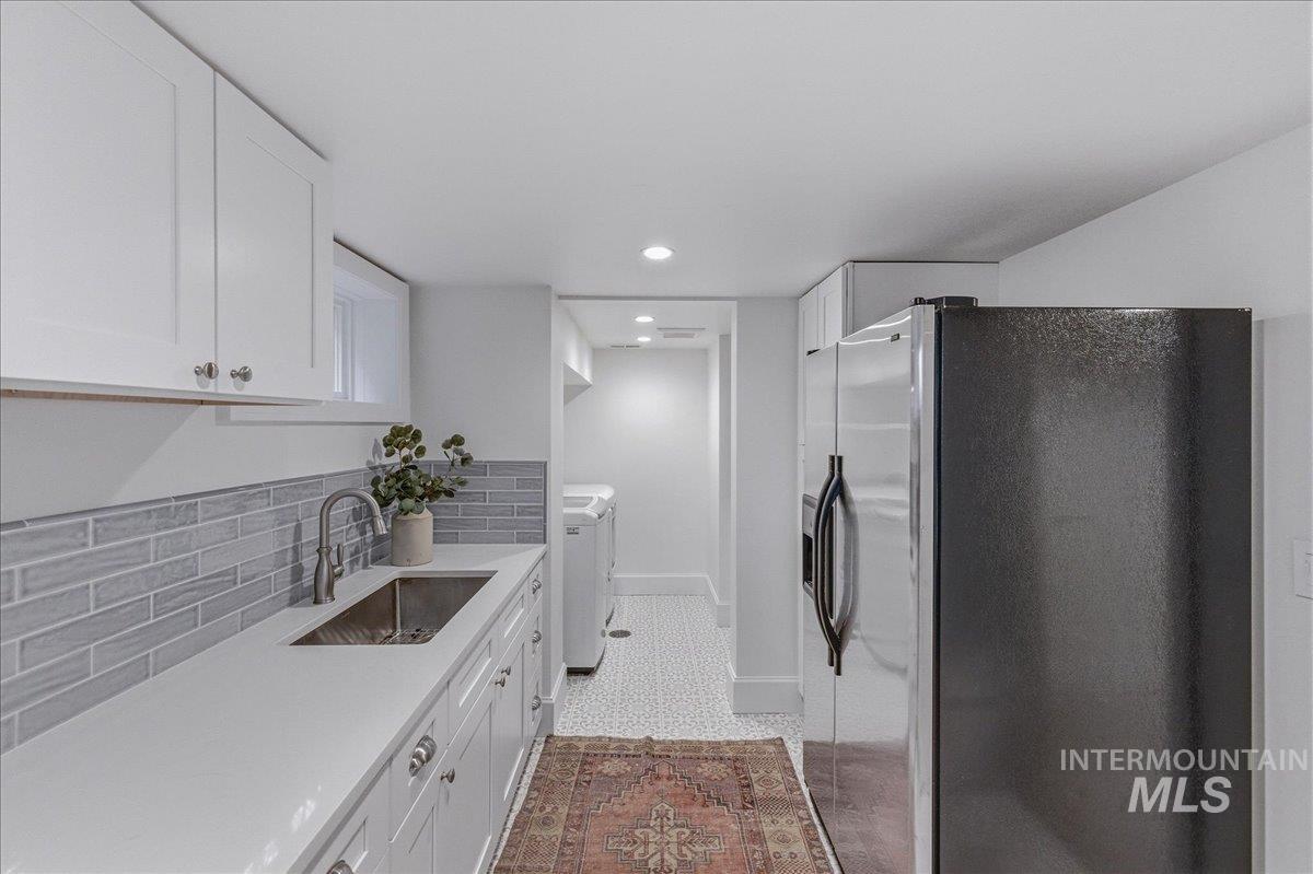 1210 North Harrison Boulevard Boise, ID 83702 - Photo 31 of 39 Kitchen with stainless steel fridge with ice dispenser, white cabinetry, recessed lighting, light stone countertops, and independent washer and dryer