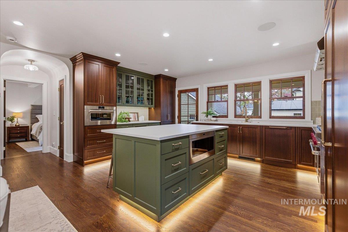1210 North Harrison Boulevard Boise, ID 83702 - Photo 10 of 39 Kitchen featuring glass insert cabinets, arched walkways, stainless steel appliances, dark wood-type flooring, and recessed lighting