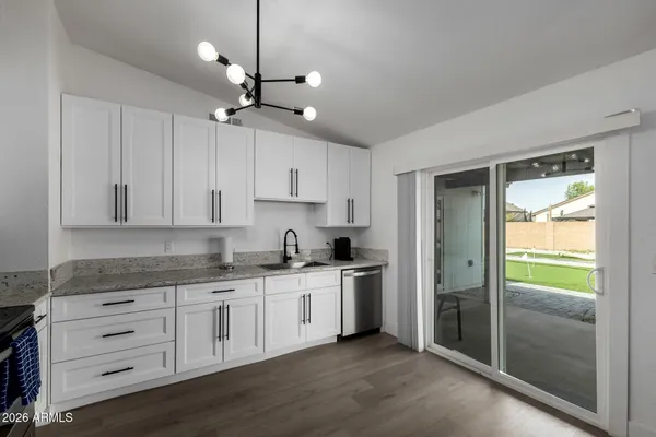 a kitchen with granite countertop a refrigerator a sink and cabinets