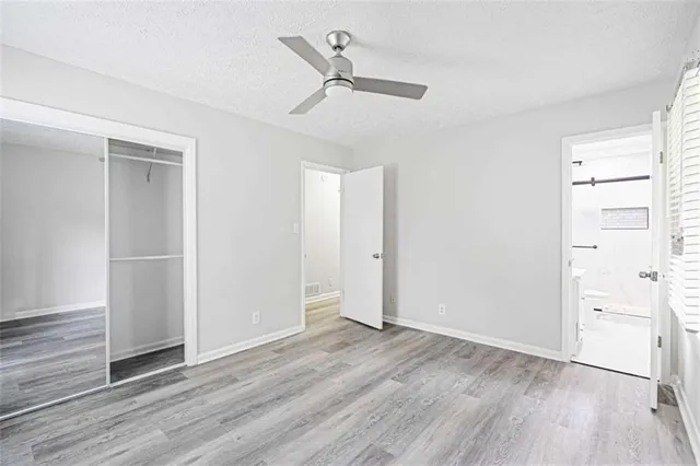 an empty room with wooden floor a ceiling fan and windows